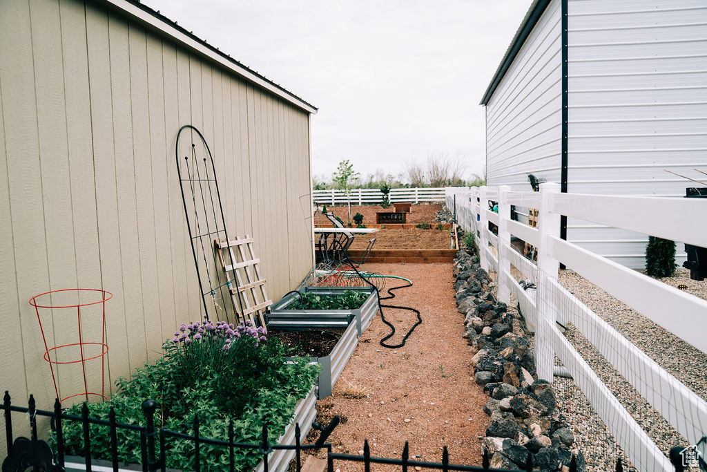 View of yard with fence and a vegetable garden