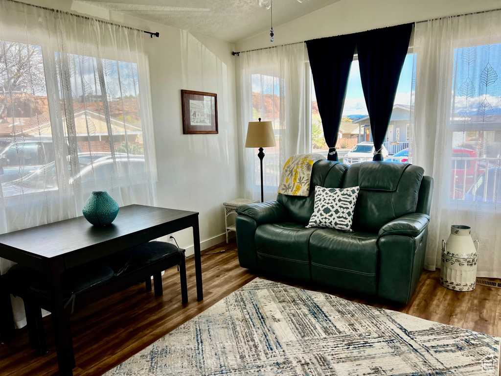 Living area with wood finished floors, baseboards, and vaulted ceiling