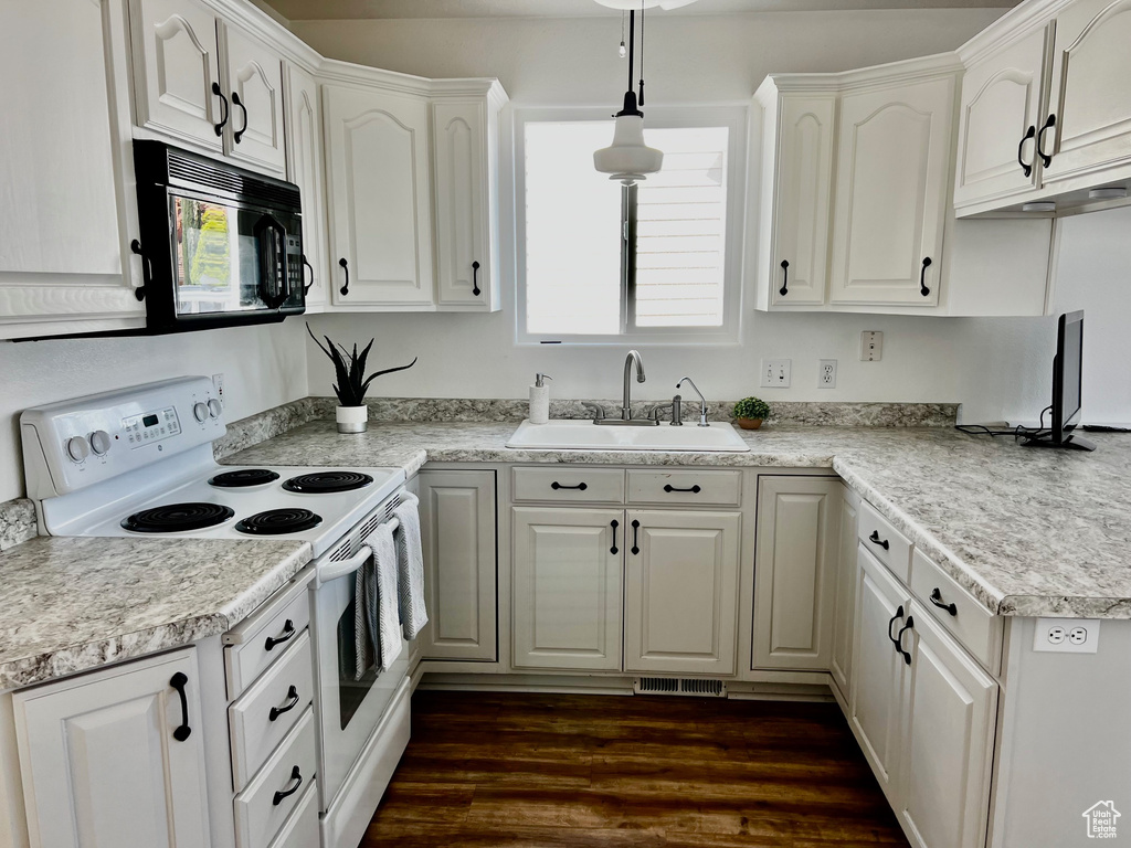 Kitchen featuring electric range, black microwave, a sink, white cabinets, and dark wood-style floors