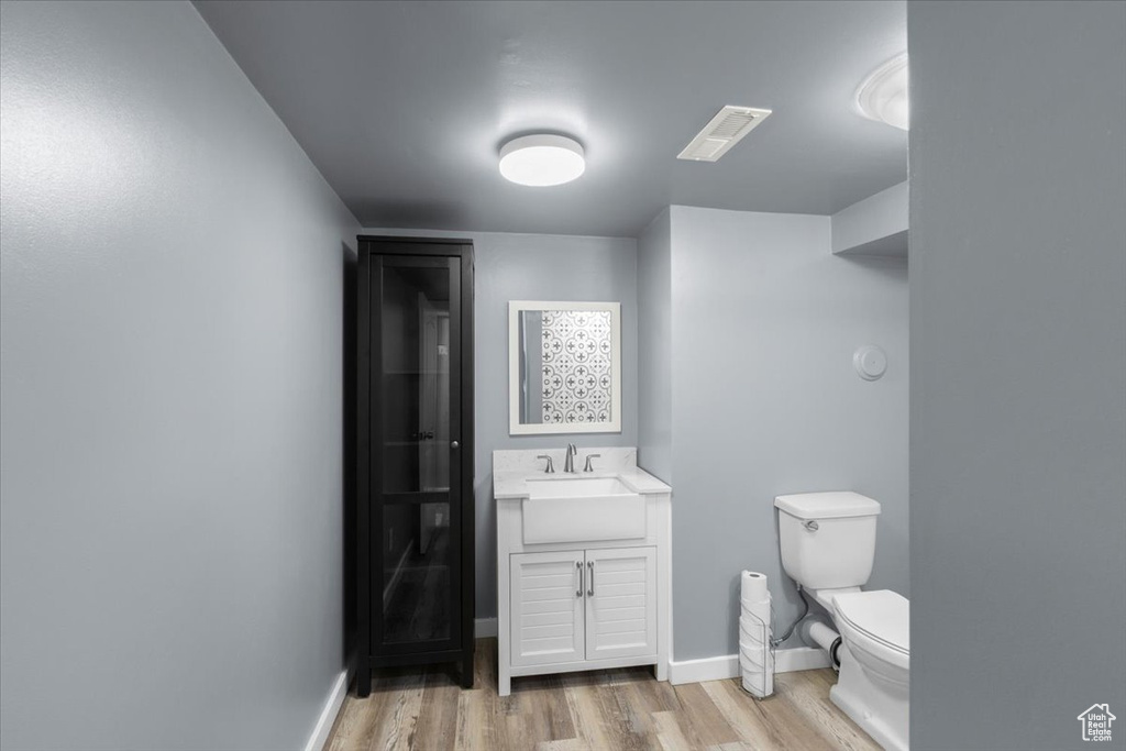 Bathroom with wood finished floors, toilet, vanity, and baseboards