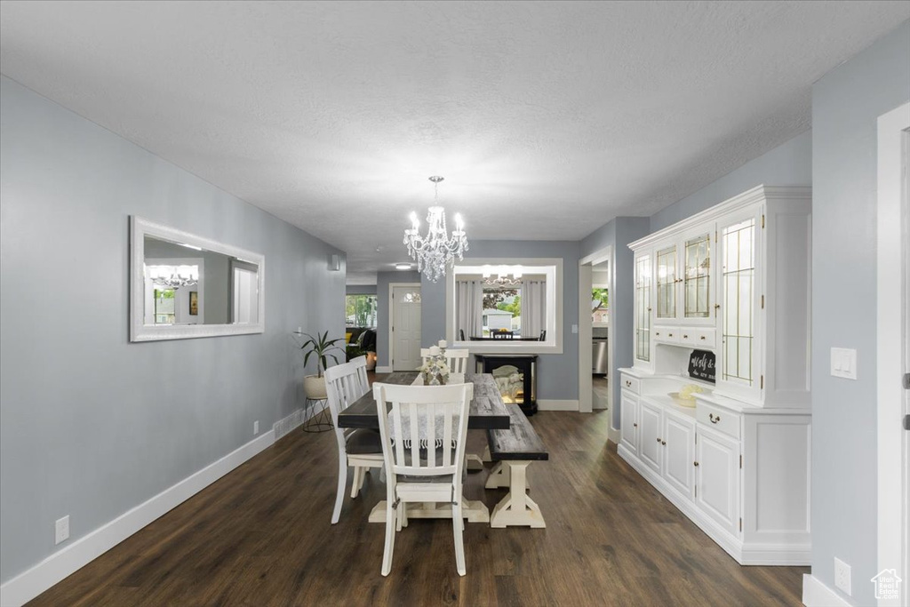 Dining space with a chandelier, baseboards, and dark wood-type flooring