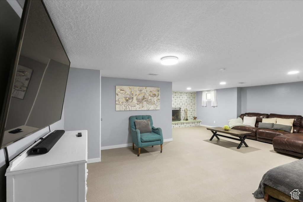 Carpeted living area with baseboards, a textured ceiling, and recessed lighting