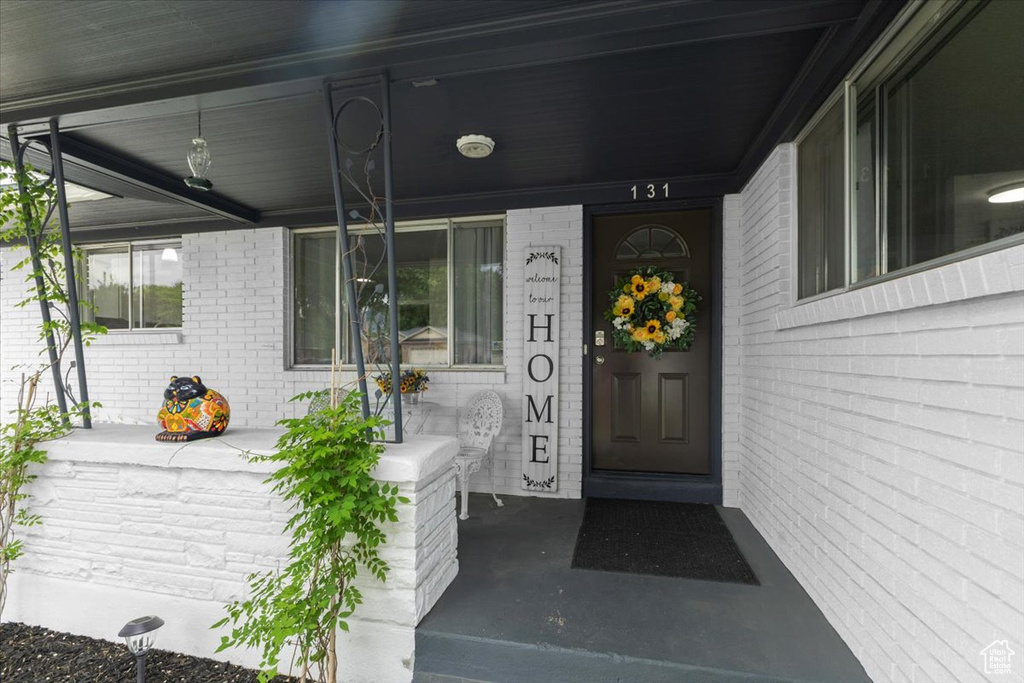View of exterior entry with covered porch and brick siding