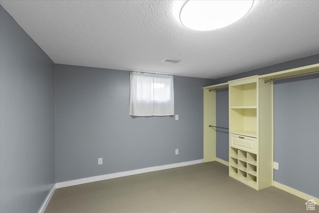 Unfurnished bedroom with a textured ceiling, carpet, and baseboards