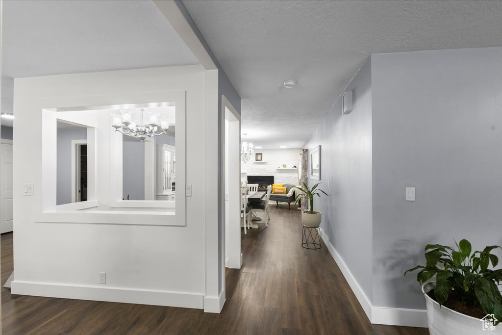 Corridor with wood finished floors, baseboards, and a chandelier