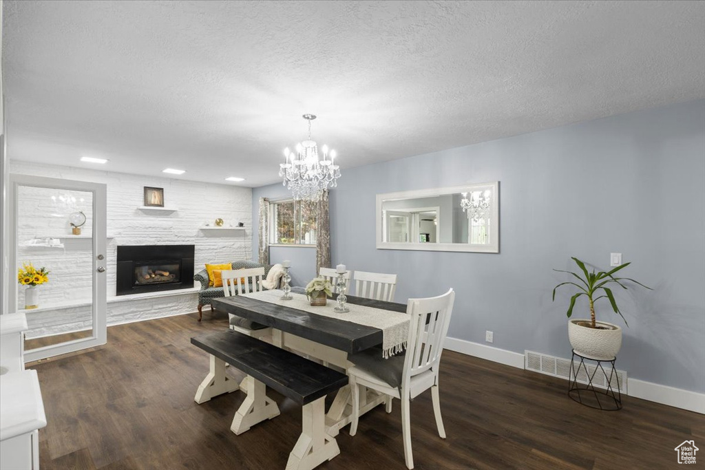 Dining room with baseboards, a chandelier, wood finished floors, a glass covered fireplace, and a textured ceiling
