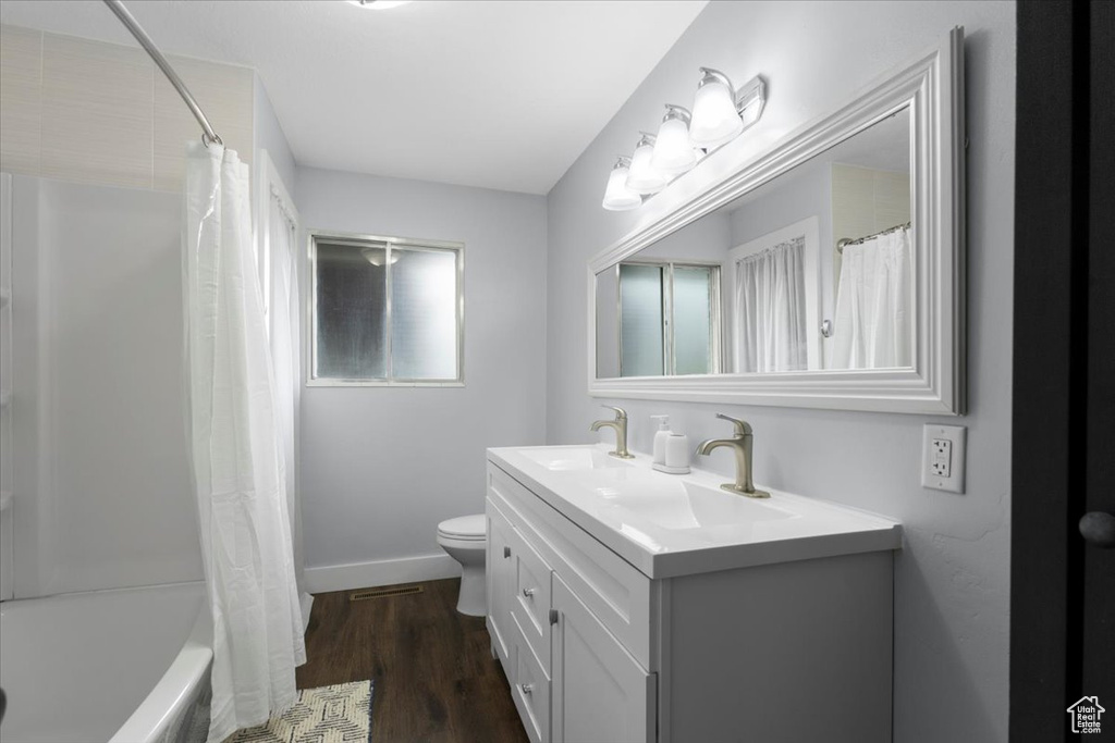 Bathroom featuring toilet, wood finished floors, vanity, and baseboards