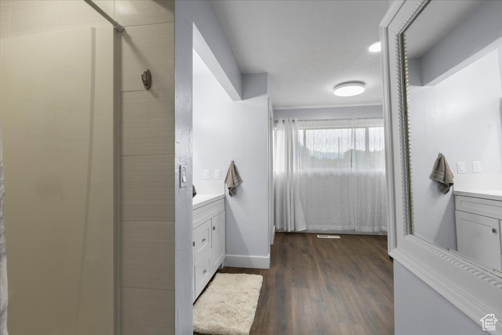 Ensuite bathroom with vanity, a shower stall, wood finished floors, and baseboards