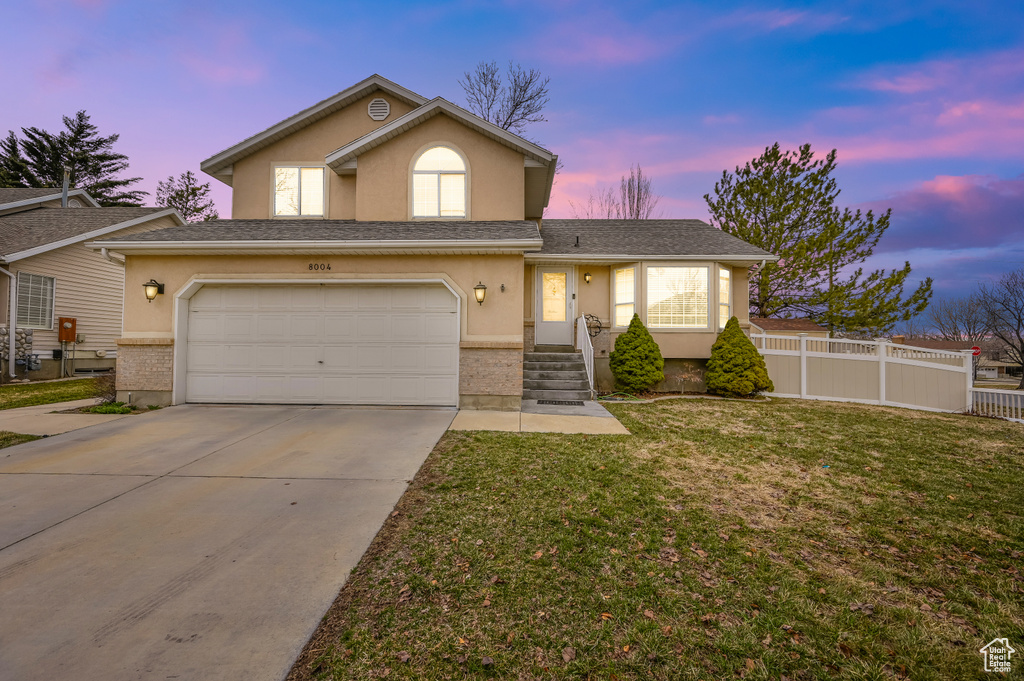 View of front of house with stucco siding, concrete driveway, an attached garage, and brick siding