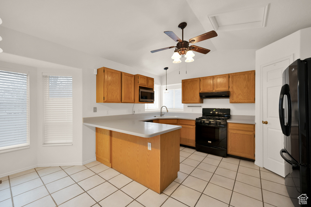 Kitchen featuring black appliances, under cabinet range hood, a peninsula, vaulted ceiling, and a sink
