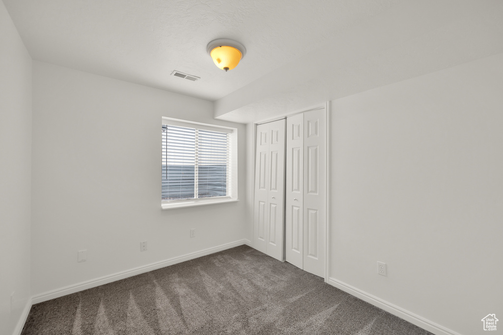 Unfurnished bedroom with dark colored carpet, baseboards, and a closet