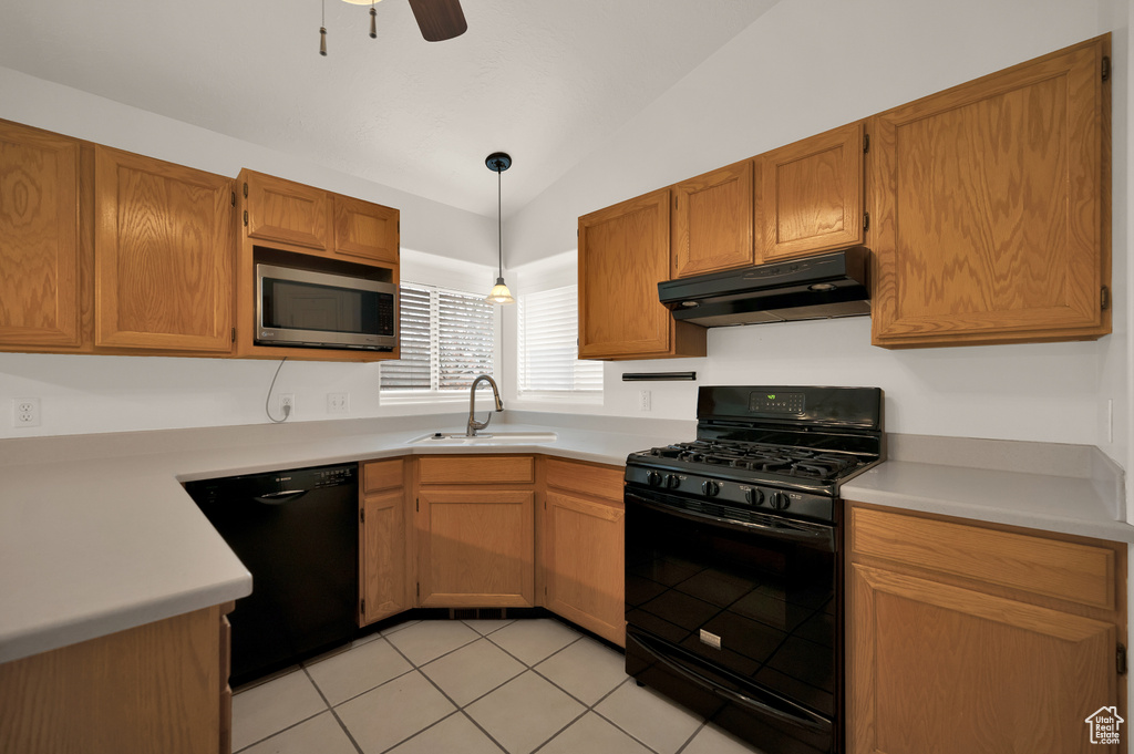Kitchen featuring black appliances, under cabinet range hood, a sink, vaulted ceiling, and light countertops