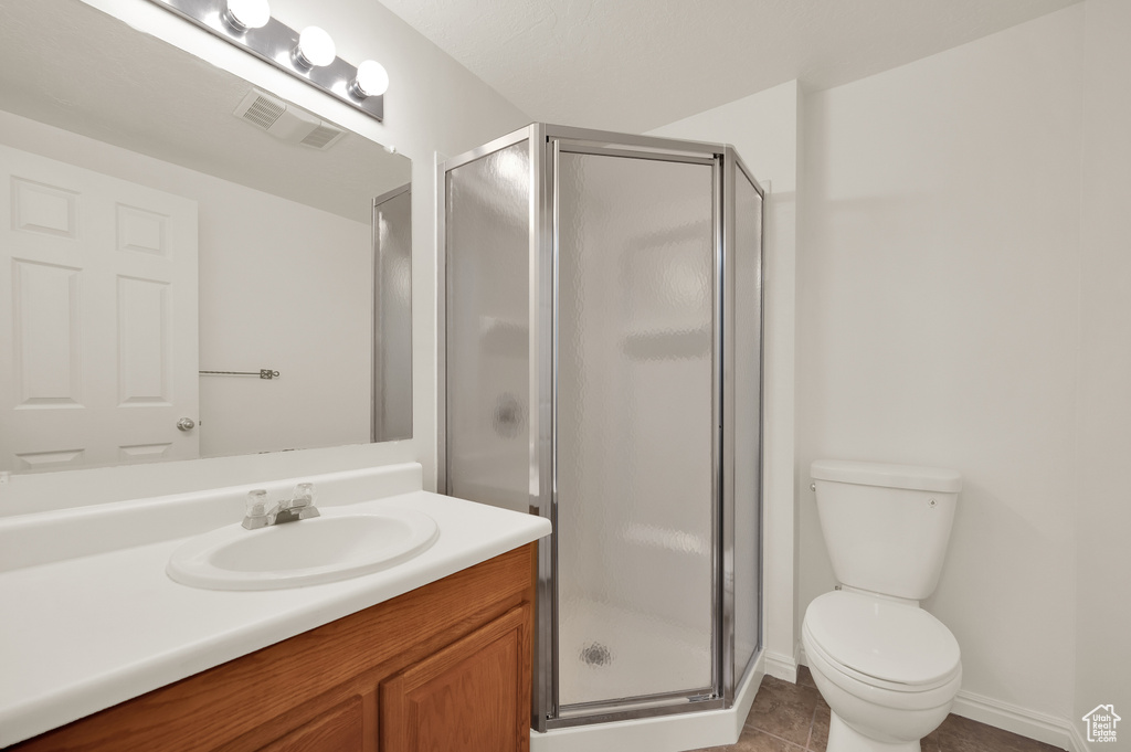 Bathroom with a stall shower, toilet, vanity, and tile patterned floors