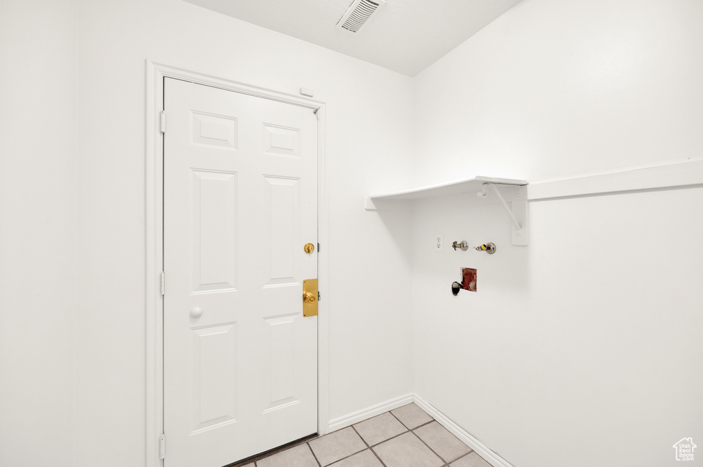 Laundry area with light tile patterned floors, hookup for a washing machine, and baseboards