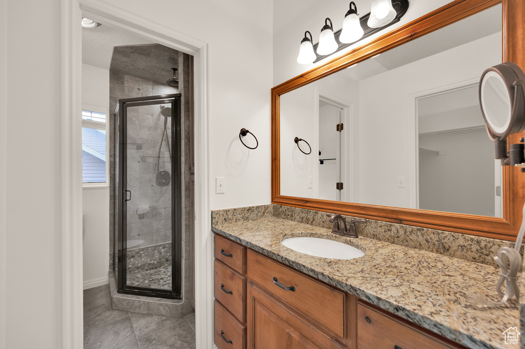Bathroom featuring a stall shower, vanity, tile patterned floors, and baseboards