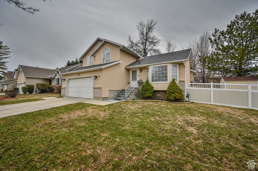 Split level home with concrete driveway, stucco siding, and a garage