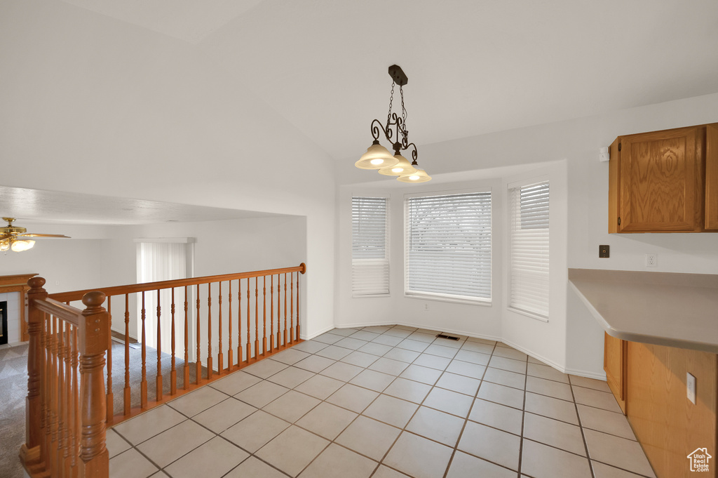 Unfurnished dining area featuring a ceiling fan, lofted ceiling, and light tile patterned flooring