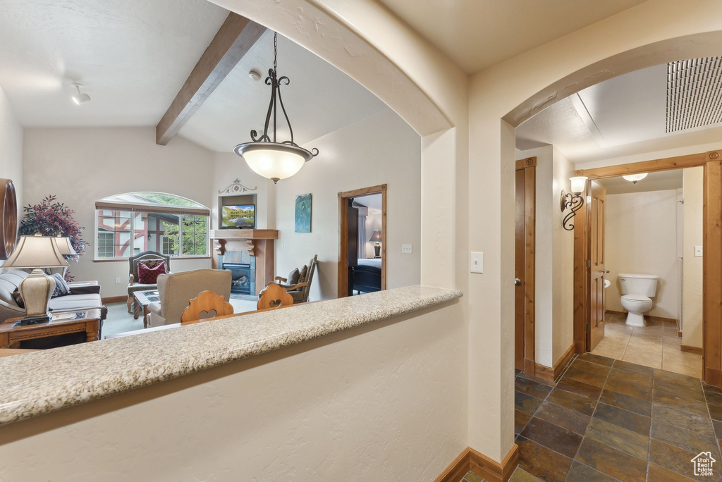 Hall with baseboards, arched walkways, and stone tile floors