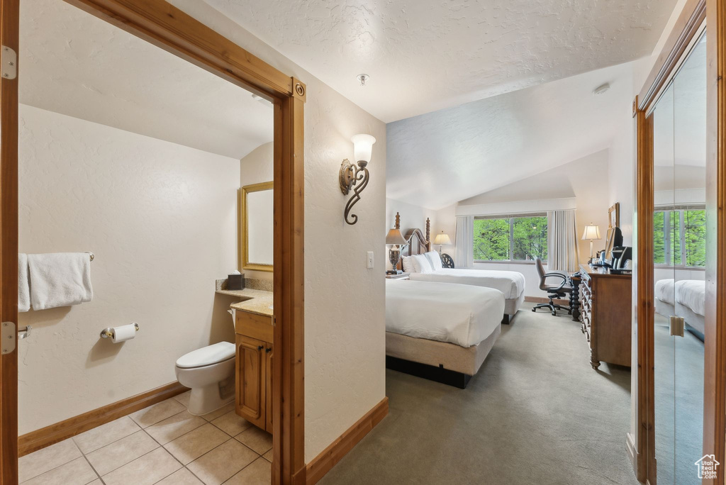 Bedroom featuring baseboards, lofted ceiling, a textured ceiling, and light tile patterned flooring