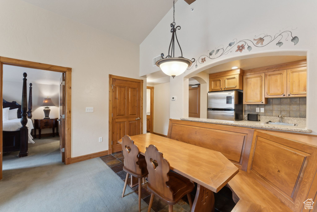 Dining area featuring high vaulted ceiling, light colored carpet, and baseboards