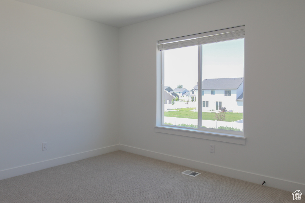 Empty room with healthy amount of natural light and light colored carpet