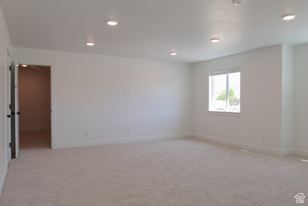 Empty room with light carpet and recessed lighting