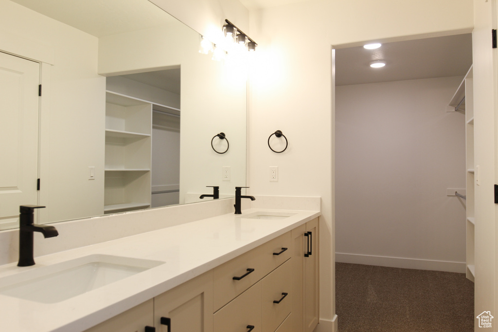 Full bath with a walk in closet, double vanity, and baseboards