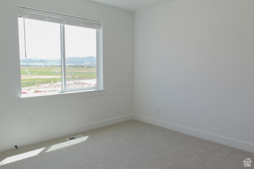 Empty room featuring light colored carpet and a mountain view