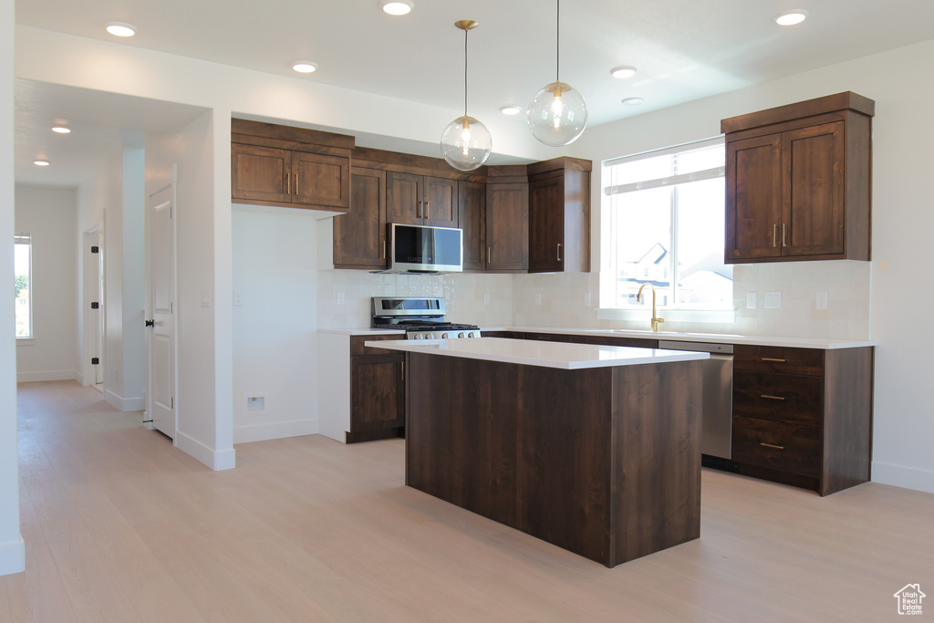 Kitchen featuring stainless steel appliances, light wood-style flooring, a center island, light countertops, and recessed lighting
