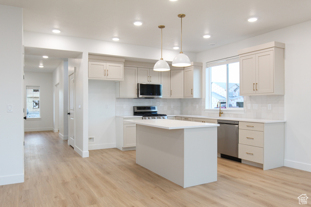 Kitchen with stainless steel appliances, a center island, light wood-style flooring, decorative backsplash, and recessed lighting