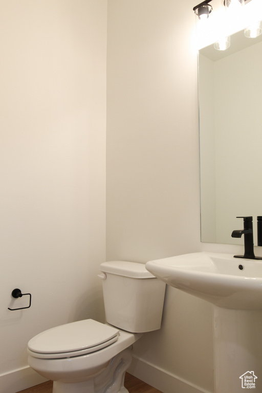 Bathroom with baseboards, toilet, wood finished floors, and a sink