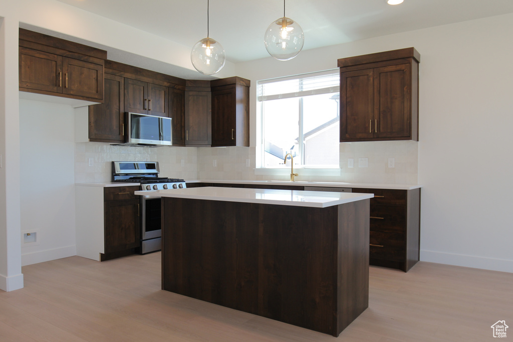 Kitchen with stainless steel appliances, backsplash, light wood-type flooring, and light countertops