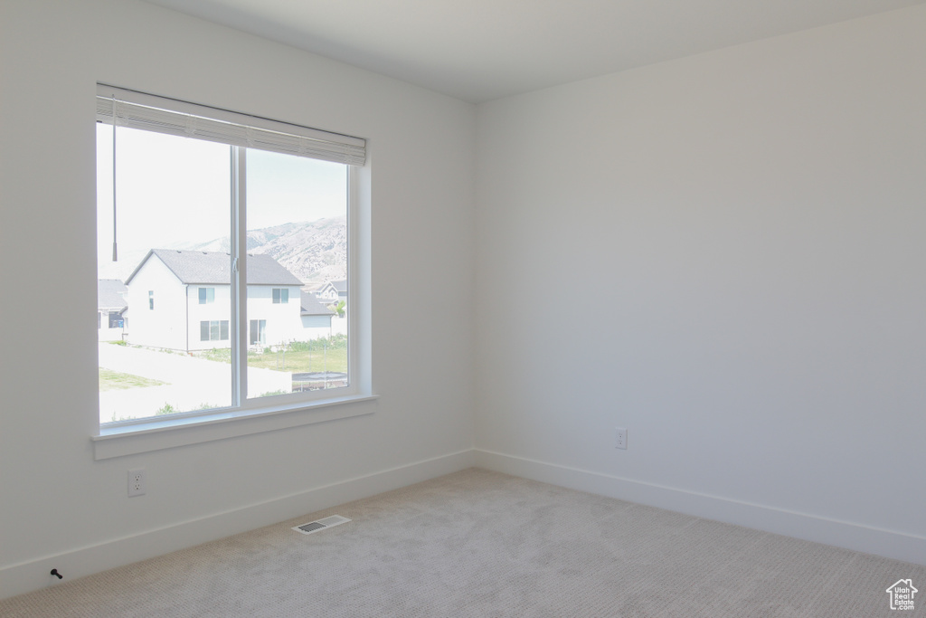 Spare room with healthy amount of natural light and light colored carpet