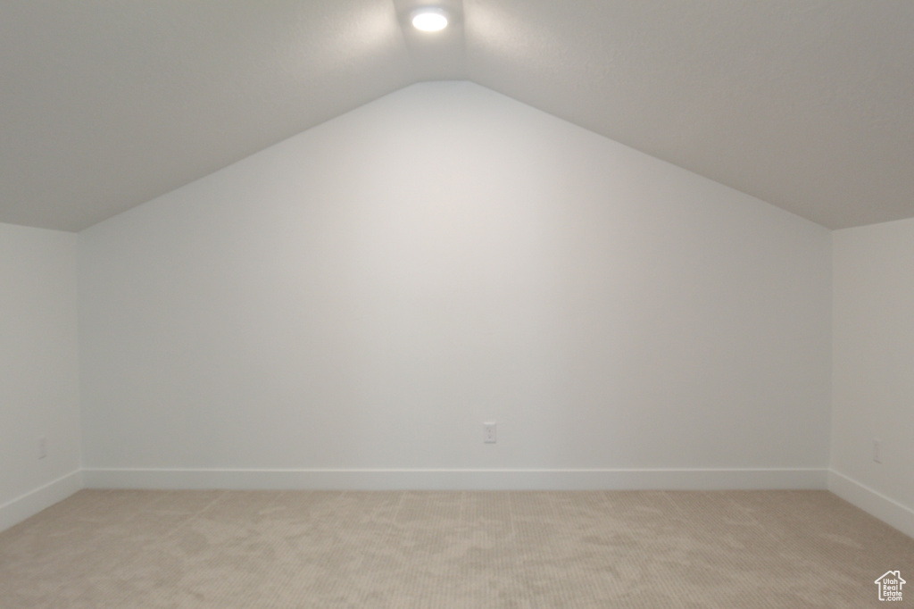 Additional living space featuring lofted ceiling and light carpet