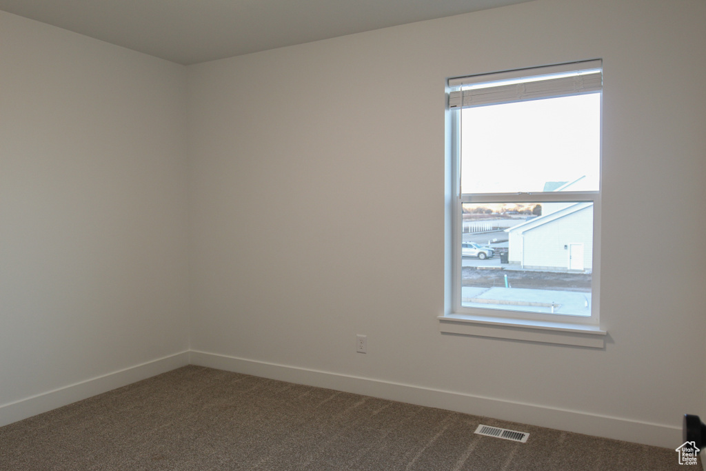 Unfurnished room featuring dark colored carpet and baseboards