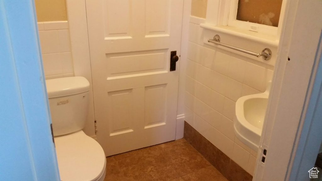 Half bath with toilet and tile walls