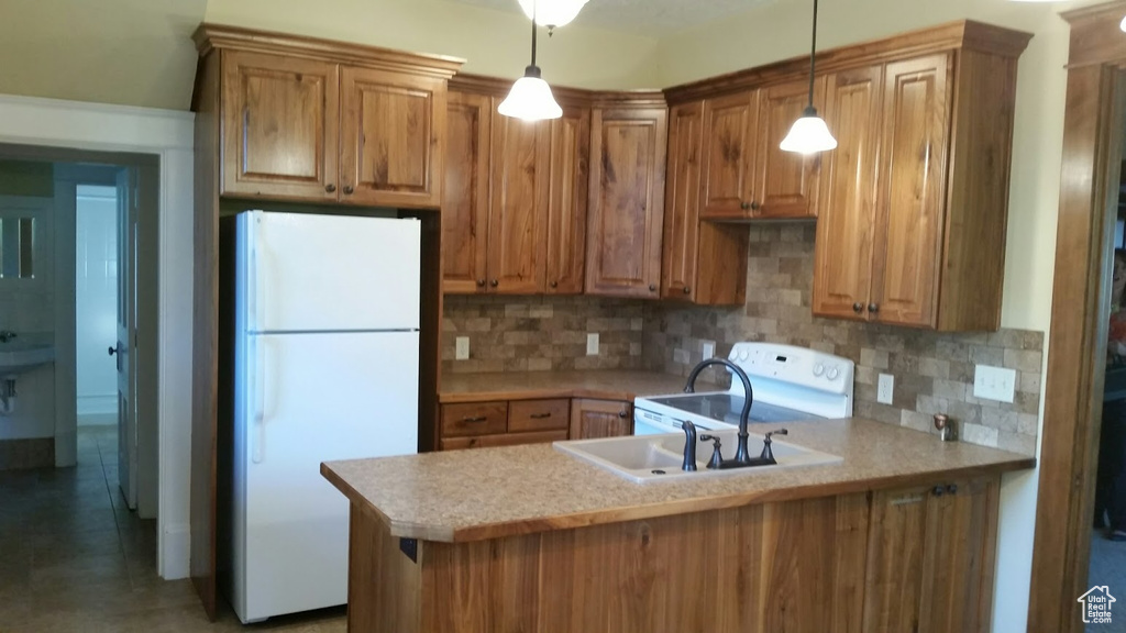 Kitchen featuring freestanding refrigerator, stove, light countertops, and a peninsula