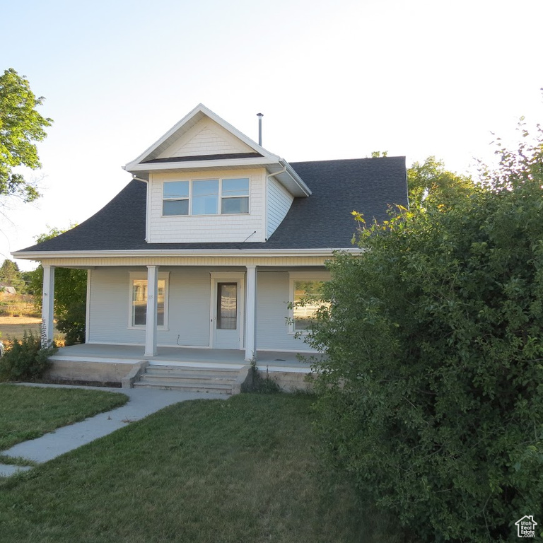 View of front of property featuring a front lawn, a porch, and a shingled roof