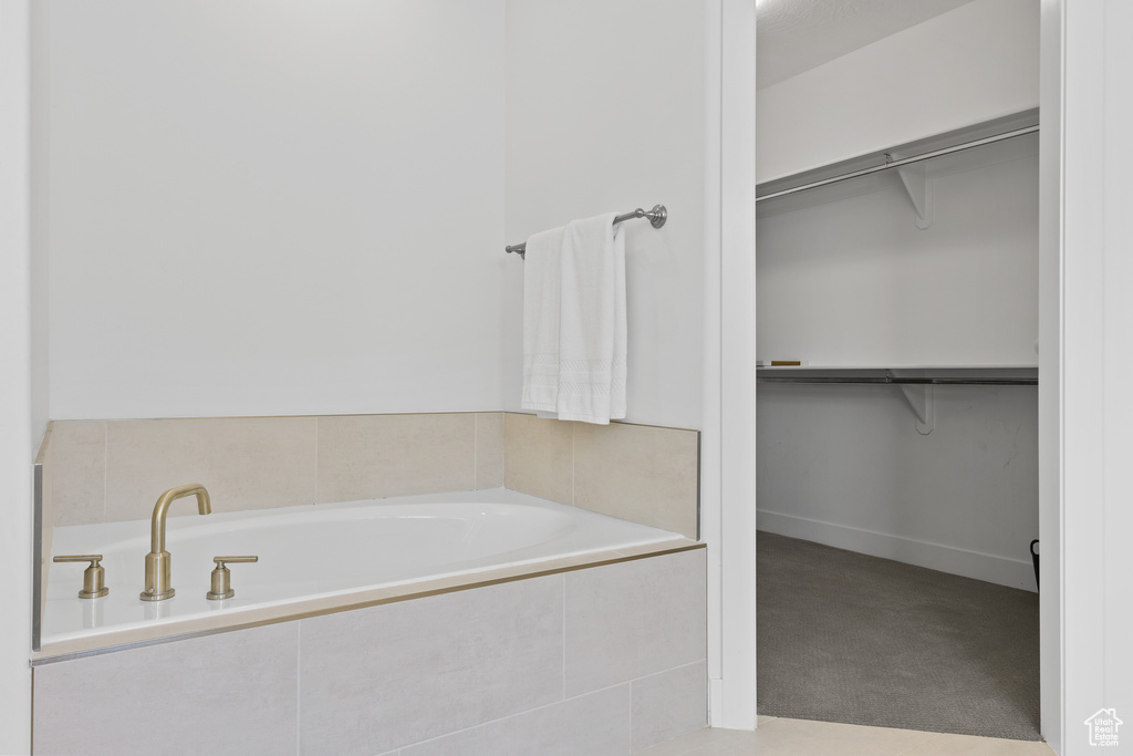 Full bath featuring a walk in closet and a garden tub
