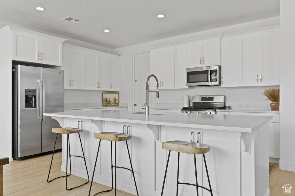 Kitchen featuring stainless steel appliances, white cabinetry, light countertops, and recessed lighting