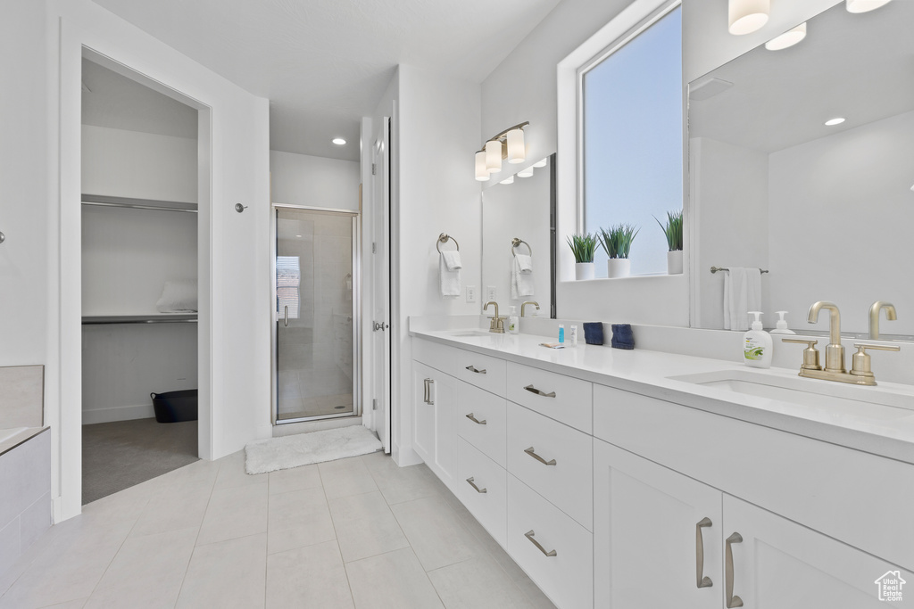 Full bath featuring a shower stall, tile patterned flooring, recessed lighting, double vanity, and a walk in closet
