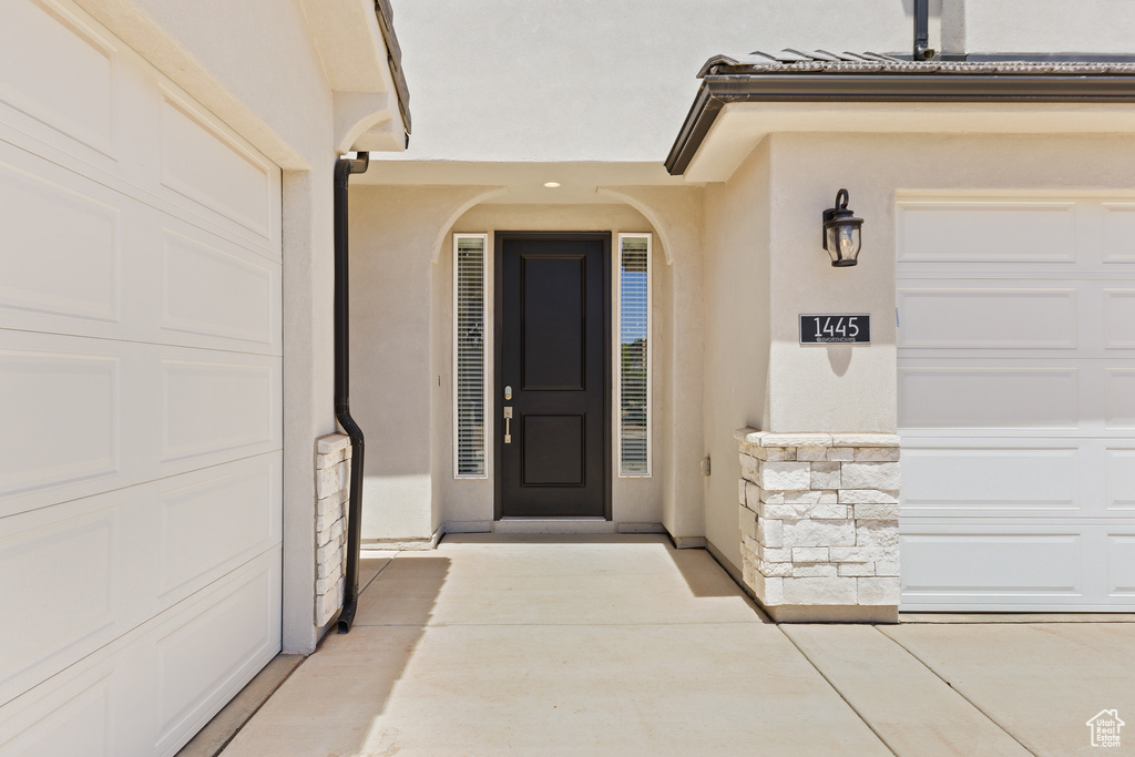 Entrance to property featuring stucco siding, a garage, and stone siding