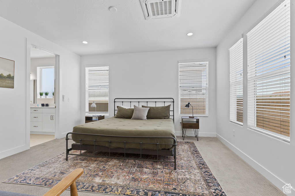 Bedroom featuring light carpet, baseboards, recessed lighting, and connected bathroom