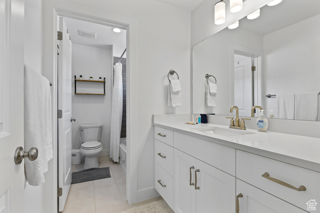 Bathroom featuring vanity, tile patterned floors, toilet, baseboards, and shower / bath combo