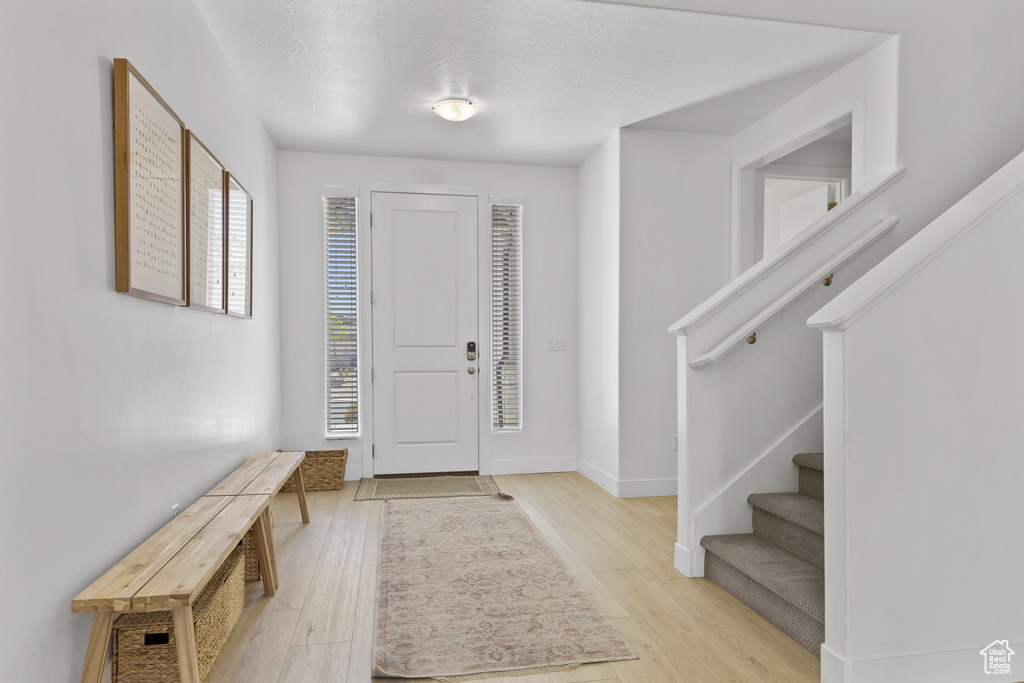 Entrance foyer featuring light wood finished floors, stairway, and baseboards