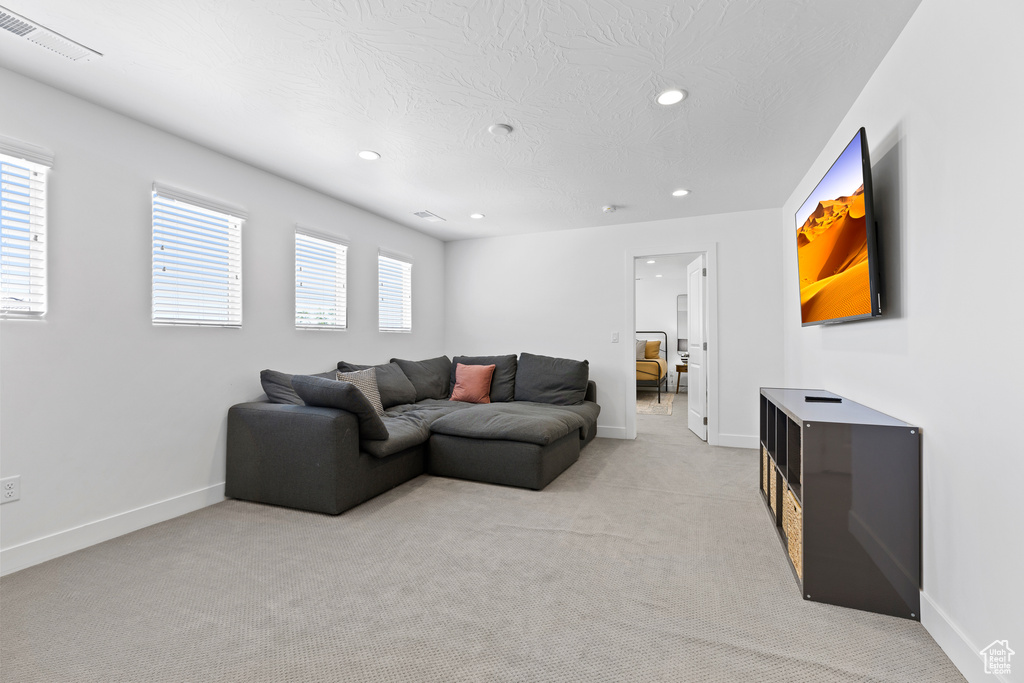 Living room with recessed lighting, light colored carpet, baseboards, and a textured ceiling