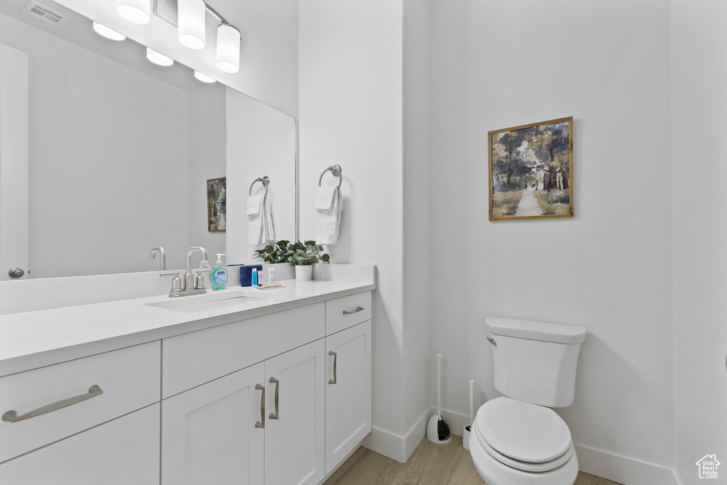 Bathroom featuring baseboards, toilet, wood finished floors, and vanity