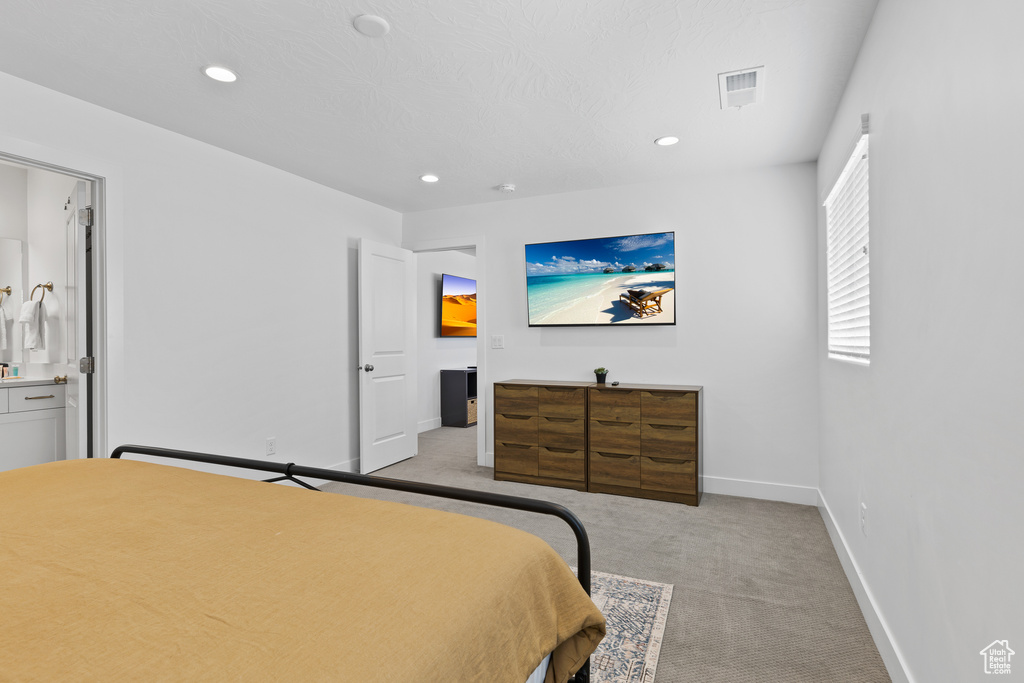 Bedroom featuring light carpet, recessed lighting, baseboards, and ensuite bath