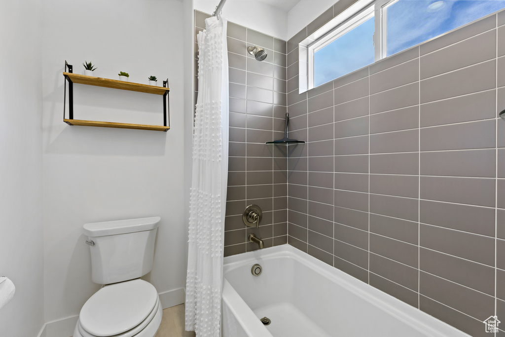 Full bathroom with toilet, baseboards, and shower / bath combo with shower curtain