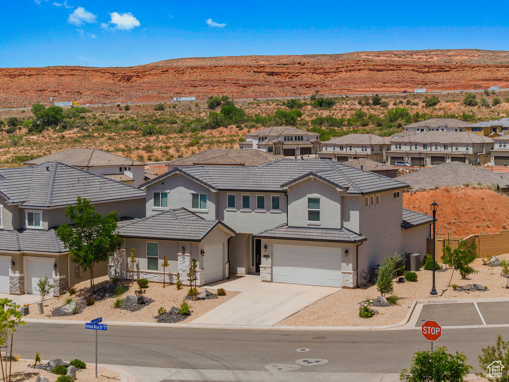 View of front of house with a garage, stucco siding, concrete driveway, stone siding, and a mountain view